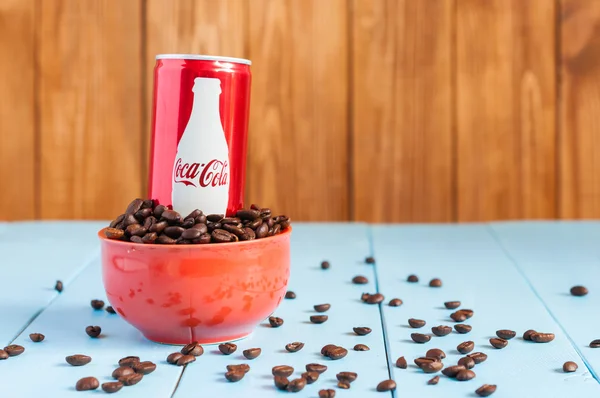 Kiev, Ukraine  April 2015. Coca-Cola in a bowl of coffee standing on blue table, dark wooden background.