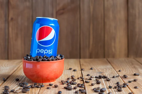 Kiev, Ukraine, April 2015. Can Pepsi cola in a bowl of coffee standing on dark wooden background with empty space. Carbonated soft drink that produced and manufactured by PepsiCo. Created, developed