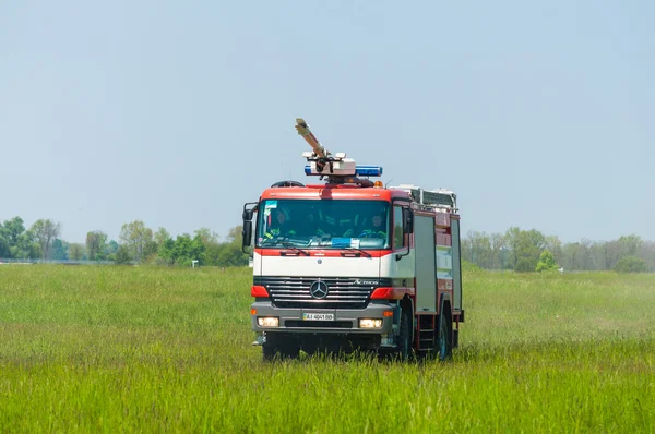 BORYSPIL, UKRAINE - MAY, 20, 2015: Fire-brigade on firetruck Mercedes with water cannon ride on alarm for instruction for fire suppression and mine victim assistance at Boryspil International Airport
