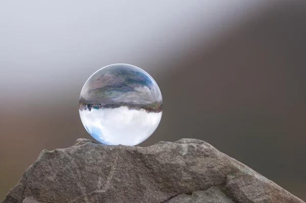 Glass transparent ball on the top of rock and dark background. Soft focus. With empty space for text