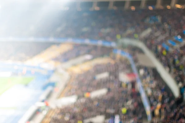 Blurred crowded football stadium. View Of the floodlit tribune of sport arena. Background with empty space for text