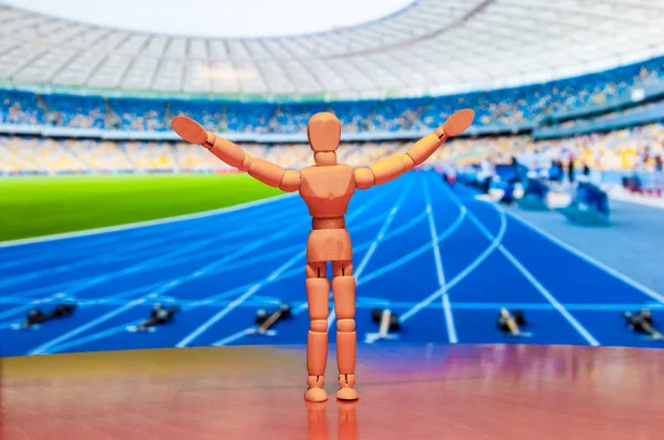 Wooden dummy, mannequin or man figurine, silhouette Of athlete standing with champion arms raised in front of stadium. Sport background