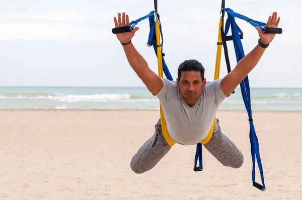 Anti-gravity Yoga, man doing yoga exercises on the sea background