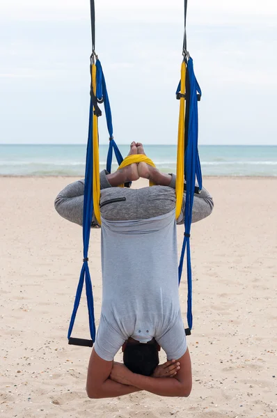 Anti-gravity Yoga, man doing yoga exercises or fly-yoga on the sea background