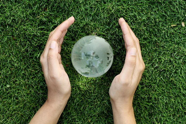 Hands protecting a glass globe