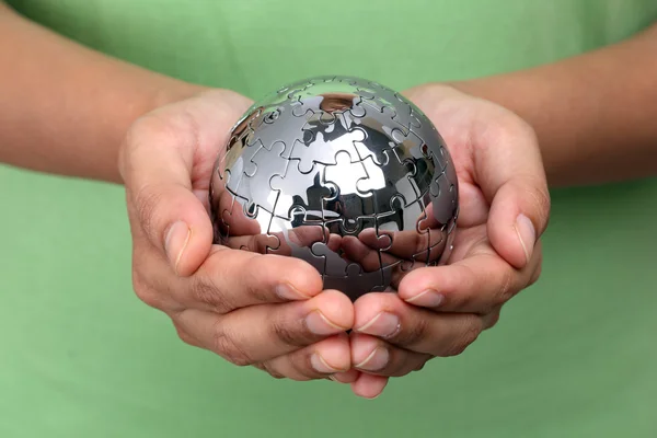 Hand holding metal puzzle globe