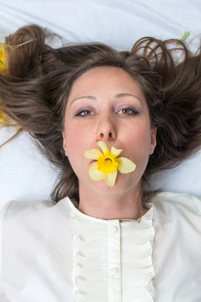Girl in bed with daffodils in her mouth