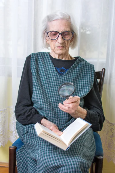 Grandma reading a book through magnifying glass