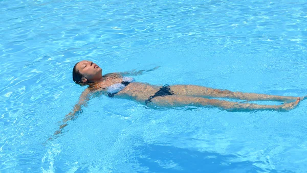 Girl floating in the water in a swimming pool