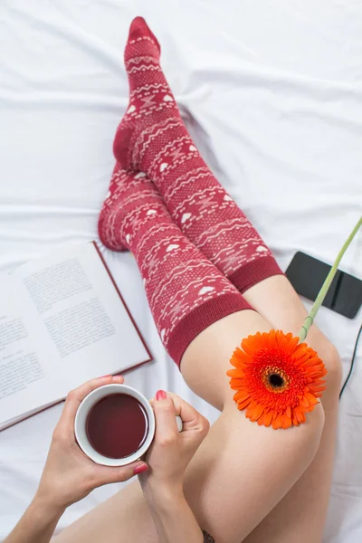 Woman holding a cup of tea in bed