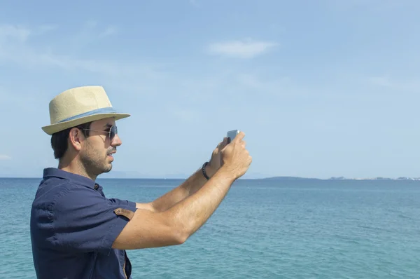Man taking photos with his cell phone at the beach
