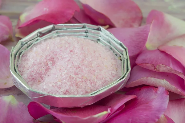 Pink aromatic bath in a bowl salt on a table decorated with rose