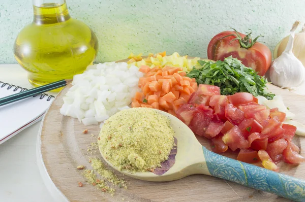 Sliced vegetables and spice in a wooden spoon ready for cooking