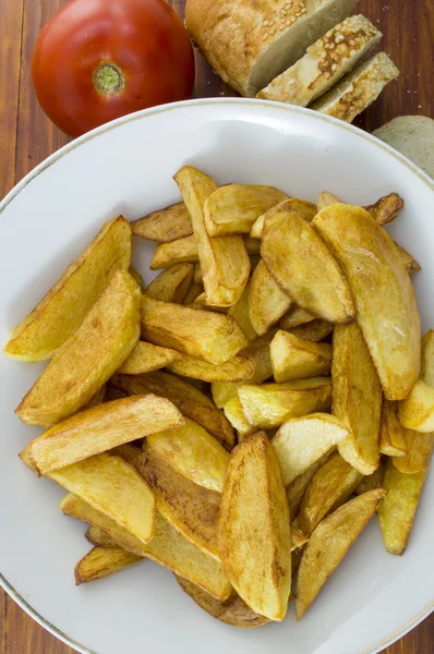 Fried potatoes on a plate decorated with sliced bread and a toma