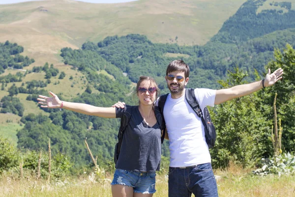 Happy couple on a hiking trip surrounded by mountains