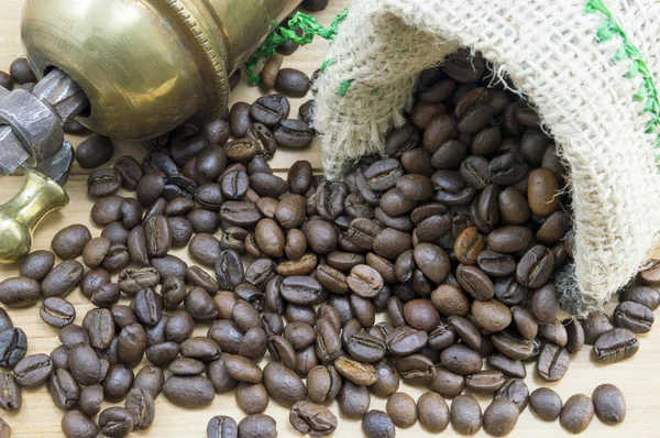 Coffee beans falling from coffee bag next to a vintage coffee gr