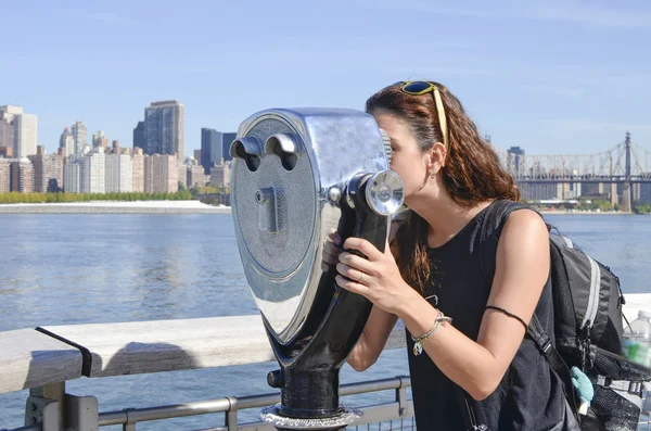 Girl looking thru public binoculars at the Manhattan view