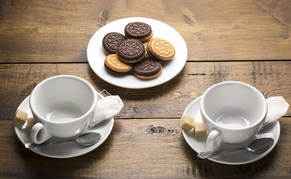 Set of two ceramic tea mugs with tea bags and plates of cookies.Preparation for brewing tea.