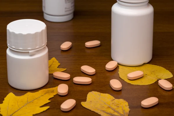 Orange pills and medicine bottle on wooden background