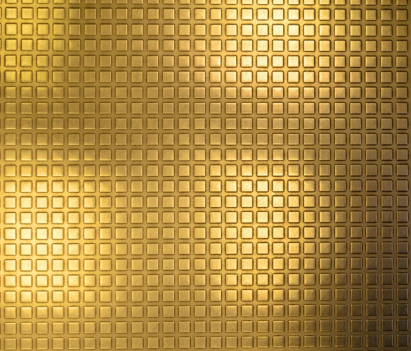 Shiny gold plated metal surface with a texture in form of small convex squares