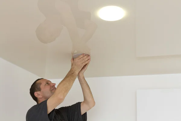 Electrician installs neatly spotlight.