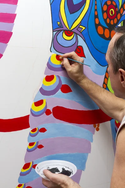 Painter paints with acrylic paints picture on the wall.