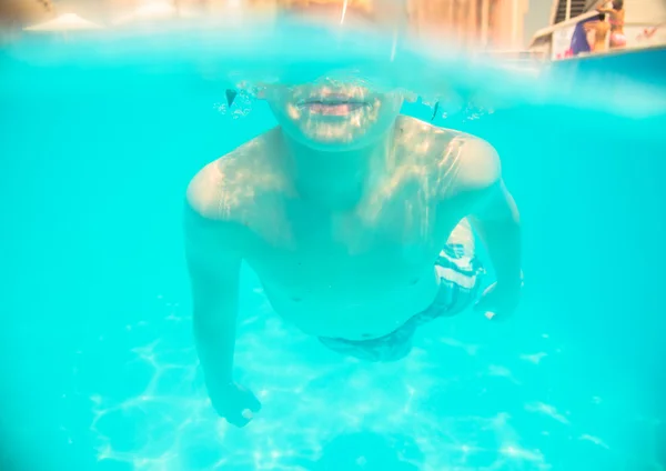 A little boy swimming underwater in the pool