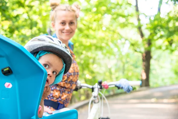 Mom on a bike with a small child, who wore a bicycle helmet and