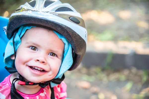 Little girl dressed in bicycle helmet and sits on a bicycle seat