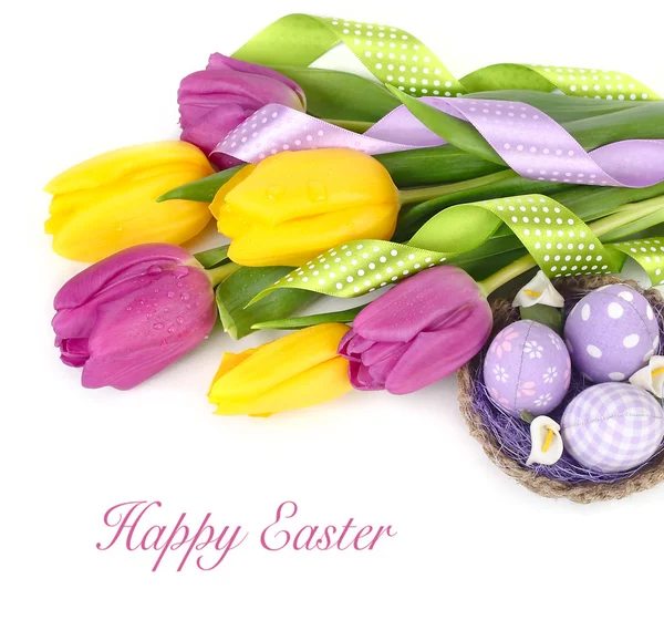 Bright spring tulips and textile Easter eggs in a nest on a white background. An easter background with the place for the text.