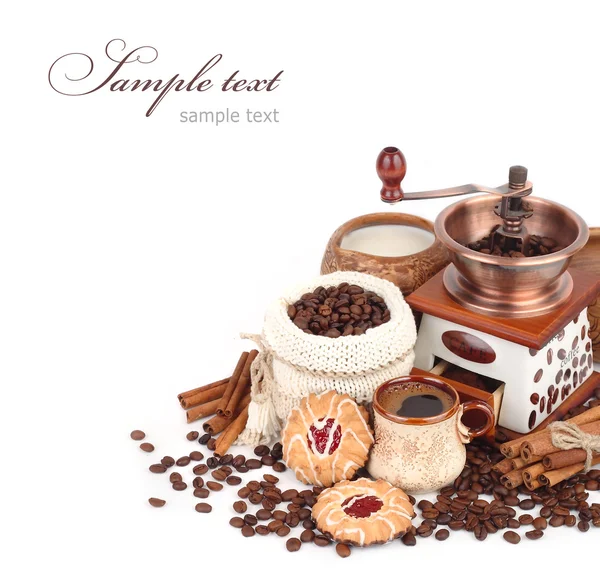 Cup of coffee with cookies, the coffee grinder and coffee grains on a white background.