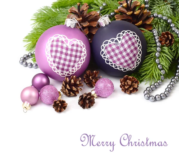 Violet Christmas balls with heart and cones on branches of a Christmas tree on a white background. A Christmas background with a place for the text.
