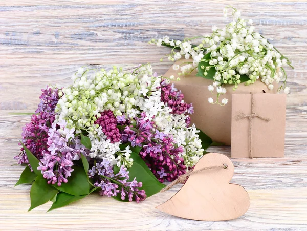 Fresh lilac, gift boxes and wooden heart (a place for the text) on a wooden background. A festive background with a place for the text.