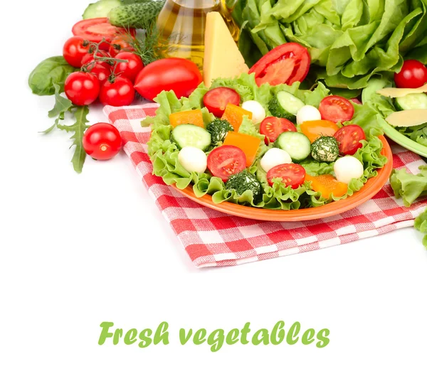 The Greek salad with cheese balls and fresh ripe vegetables and herbs on an orange plate and on a white background with a place for the text.