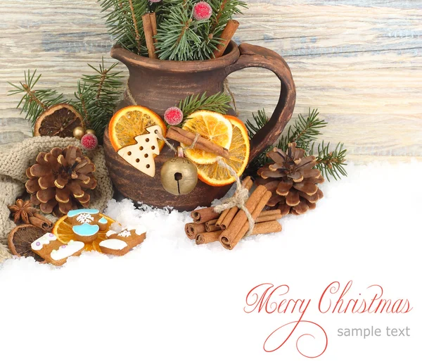 Christmas ginger cookies, cones, nuts and dried oranges and a clay jug on snow on a wooden background. A Christmas background with a place for the text.