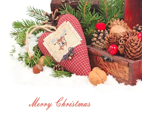 Textile checkered heart with a deer on branches of a Christmas tree near a wooden chest with cones on a white background. A Christmas background with a place for the text.