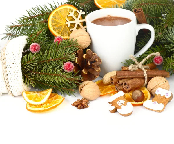 Mug of hot chocolate with ginger cookies, dried oranges, nuts and cinnamon on branches of a Christmas tree on a white background. A Christmas background with a place for the text.