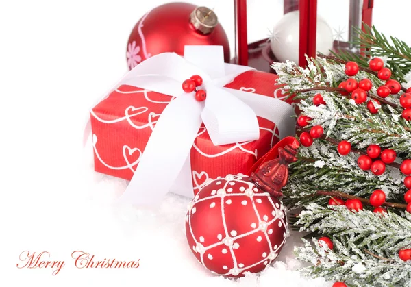 Red gift box, Christmas balls and red berries on snow on a white background. A Christmas background with a place for the text.