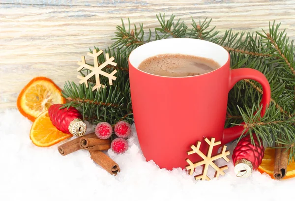 Red mug of hot chocolate, dried oranges and cinnamon on snow on a white background. A Christmas background with a place for the text.