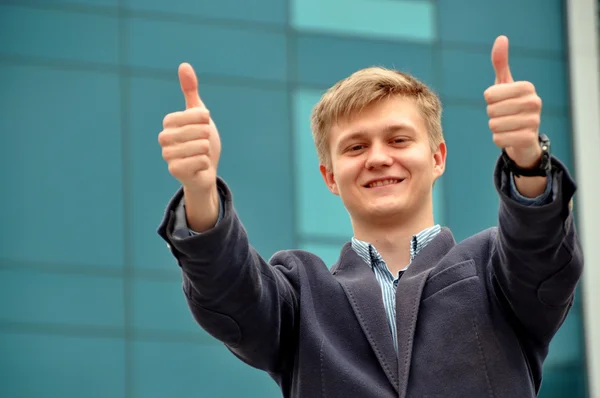Businessman shows thumbs up with both hands while smiling.