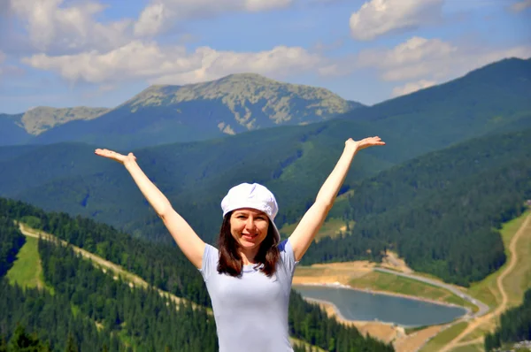 Happy girl with raised arms on a background of mountains