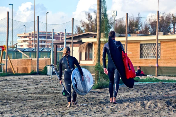 Two surfers of different generations run back from the beach after an early morning session.