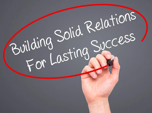 Man Hand writing Building Solid Relations For Lasting Success wi