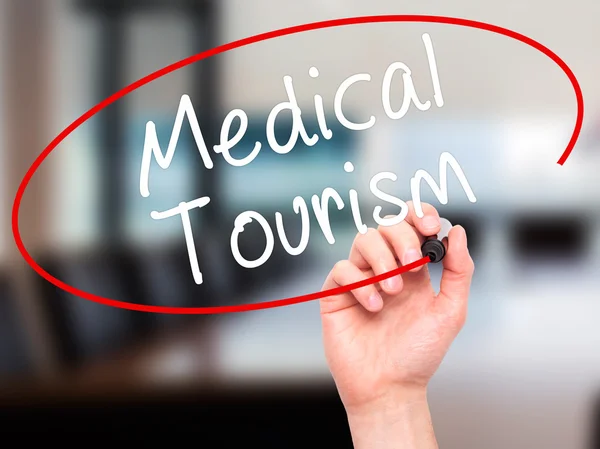 Man Hand writing Medical Tourism with black marker on visual scr