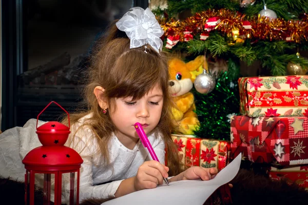 Little pretty girl writes a letter to Santa.