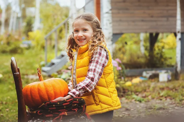 Happy child girl picking fresh pumpkins on the farm. Country living concept, growing vegetables on farm
