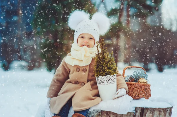 Cute baby girl enjoying winter walk in snowy park, wearing warm hat and coat