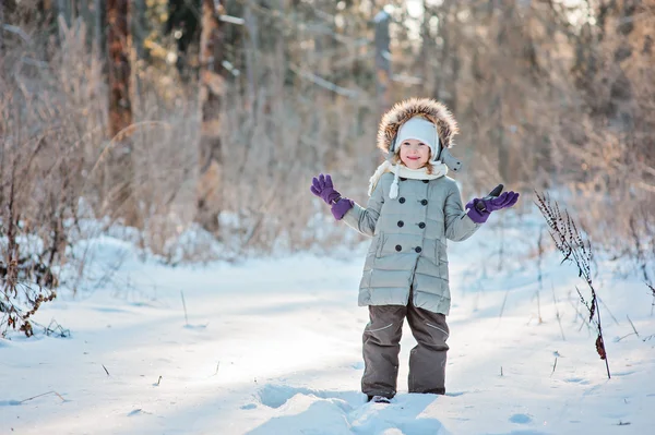 Cute happy child girl having fun in winter snowy forest