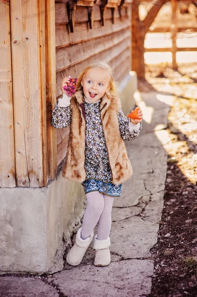 Happy child girl with handmade chicken for easter at wooden country house