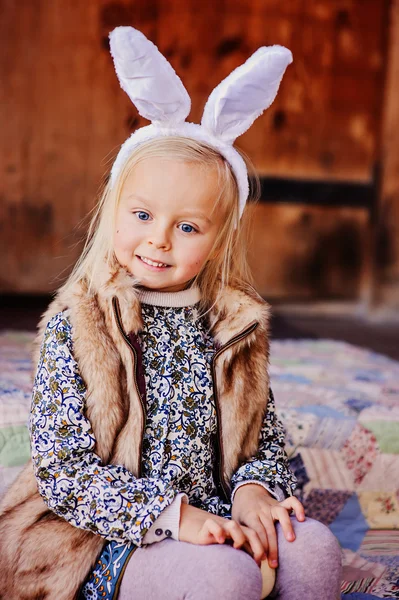 Happy child girl wearing bunny ears for easter at wooden country house